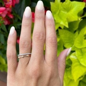 rose gold bamboo gold band ring stacked with white gold pave diamond band on top on womens left hand ring finger in front of leaves