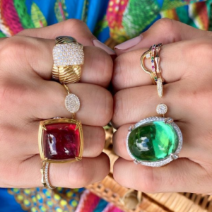 gold and diamond and colored stone rings on model with colorful background