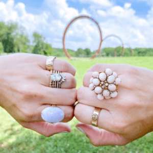 gold and diamond and colored stone rings on model with outdoor background