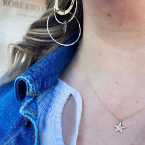 gold necklace with star diamond pendant and gold and silver earrings on model