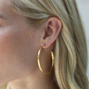 Woman wearing julie vos yellow gold plated crescent hoop earring.