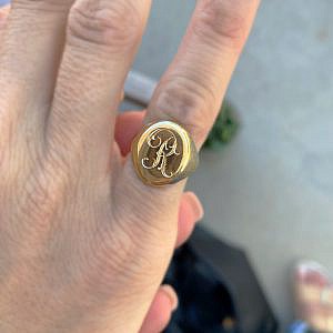 signet ring with "R" engraving on pinky finger