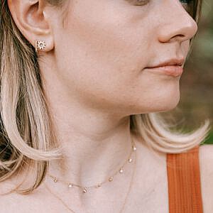 woman wearing two necklaces, one is a gold circle pendant with diamonds.